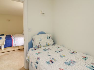 A small bedroom with a single bed and patterned bedding next to a doorway leading to another bedroom at West Dairy near Newport Pembrokeshire