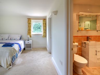 A bedroom with a bed a nightstand and a window next to a bathroom with a toilet and a sink at West Dairy near Newport Pembrokeshire