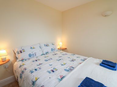 A bedroom with a bed with printed bedding and two bedside lamps at West Dairy near Newport Pembrokeshire