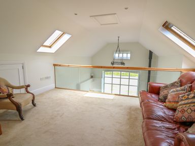 A loft area with a leather sofa and an armchair near skylight windows at West Dairy near Newport Pembrokeshire