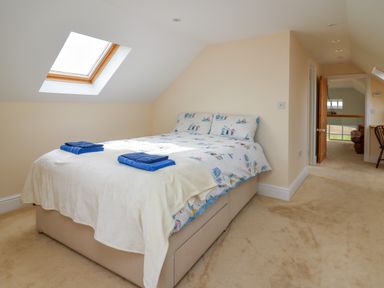 A bedroom with a bed covered in a patterned duvet and two folded blue towels near a skylight window at West Dairy near Newport Pembrokeshire