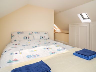 A bedroom with a bed with patterned bedding and folded towels near a skylight window at West Dairy near Newport Pembrokeshire