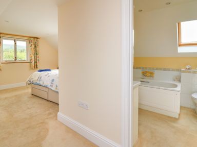 A bedroom with a bed and window next to a bathroom with a bathtub and skylight at West Dairy near Newport Pembrokeshire