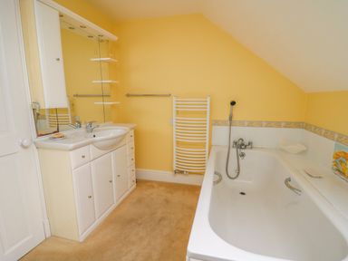 A bathroom with a sink and cabinet unit a bathtub and a towel radiator at West Dairy near Newport Pembrokeshire
