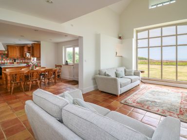 A living room with two sofas a rug and a large window overlooking a garden at West Dairy near Newport Pembrokeshire