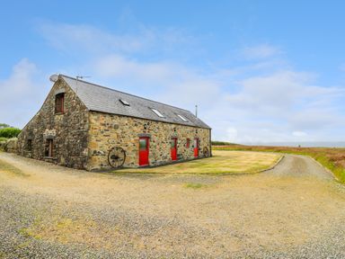 A stone building with red doors and a gravel driveway at West Dairy near Newport Pembrokeshire