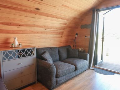 A living room with a gray sofa a gray chest of drawers and an open door at Paradise Kenstone near Hodnet