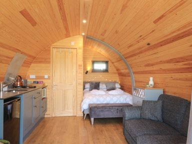 A wooden cabin interior with a bed a kitchen area and a sofa at Paradise in Kenstone near Hodnet