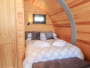 A bedroom with a double bed with pillows and folded towels in a wooden cabin at Paradise Kenstone near Hodnet