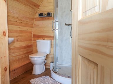 A bathroom with a toilet a shower enclosure and wooden paneling at Paradise in Kenstone near Hodnet