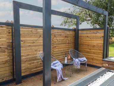 An outdoor seating area with two chairs and a small table on wooden decking at Paradise Kenstone near Hodnet