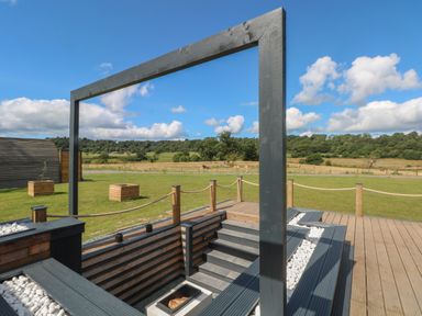 An outdoor sunken seating area with steps and wooden framing overlooking a grassy field at Paradise in Kenstone near Hodnet