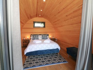 A bedroom with a double bed blue pillows bedside tables lamps and a geometric rug at Hawkstone in Kenstone near Hodnet