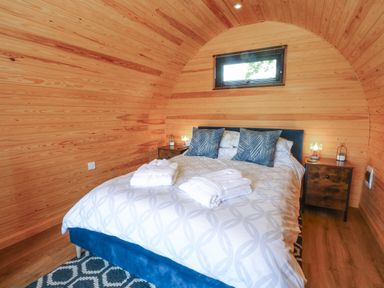 A bedroom with a double bed and bedside tables inside a wooden cabin at Hawkstone Kenstone near Hodnet