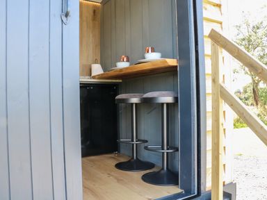 A small seating area with two stools and a counter with tableware at Hawkstone Kenstone near Hodnet