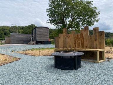 An outdoor area with a fire pit and wooden bench at Hawkstone in Kenstone near Hodnet