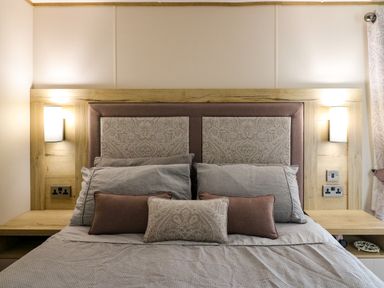 A bedroom with a bed and multiple pillows and a patterned headboard at Osprey 6 Kiln Park Tenby