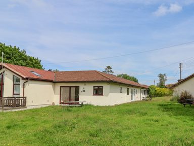 A single-story building with a tiled roof and grassy lawn with picnic tables at Seaweed Weston near Sidmouth