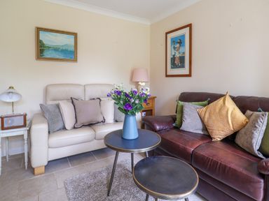 A living room with two sofas and a vase with flowers on a table at Seaweed in Weston near Sidmouth