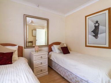 A bedroom with two single beds a bedside table with lamp a large wall mirror and framed artwork at Seaweed Weston near Sidmouth