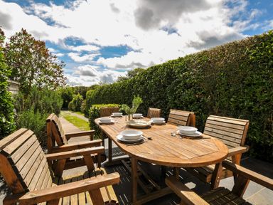An outdoor dining setup with wooden table and chairs at 2 Glyddins 1910, Rock
