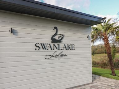 The exterior wall of a building with a swan logo and the text Swanlake Lodges next to a palm tree