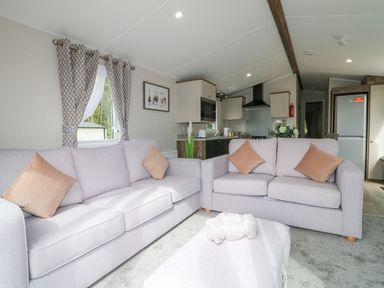 A living room with two sofas and a rolled blanket on an ottoman at Stork Lodge in Swannington near Coalville