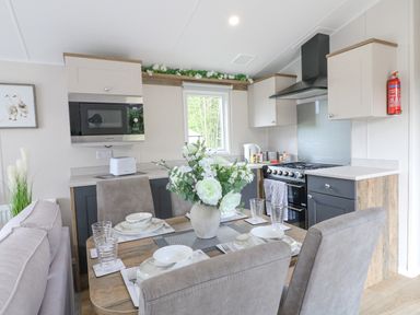 A kitchen and dining area with a table set for four and appliances at Stork Lodge in Swannington near Coalville