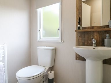 A bathroom with a toilet and a sink under a mirror at Stork Lodge in Swannington near Coalville