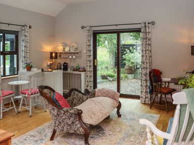 A sitting room with antique sofa cushions and chairs near a sliding glass door at Pink Granite Garden of Ireland near Tinahely County Wicklow