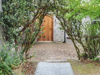 A gravel courtyard with trees and shrubs framing a wooden door at Pink Granite Garden of Ireland near Tinahely County Wicklow