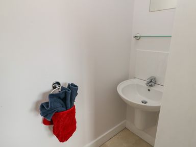 A small bathroom corner with a white sink and towels hanging on a ring at Dunes in Rhosneigr