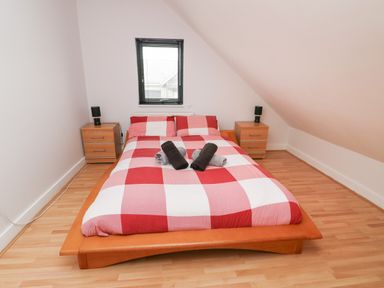 A bedroom with a double bed and two bedside tables with lamps at Dunes in Rhosneigr