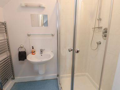 A bathroom with a pedestal sink mirror towel rack and enclosed shower at Dunes in Rhosneigr