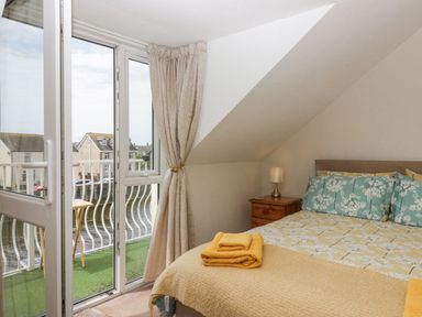 A bedroom with a double bed bedside table and lamp next to a balcony with glass doors at Lazey Cottage in Haverigg