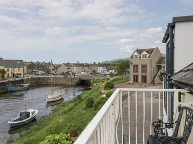 A view of boats on a river and houses from a balcony at Lazey Cottage in Haverigg