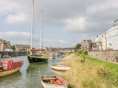 A small harbor with several boats moored near houses and grassy bank at Lazey Cottage in Haverigg