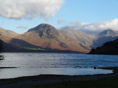 A lake with mountains in the background under a partly cloudy sky at Lazey Cottage in Haverigg
