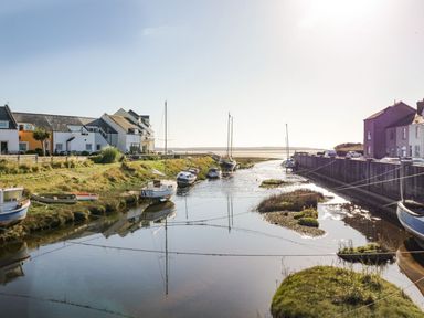 A river with moored sailboats between houses on both sides at Lazey Cottage in Haverigg