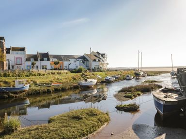 A small river with boats docked alongside houses in a coastal village at Lazey Cottage in Haverigg