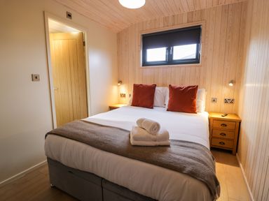 A bedroom with a bed towels and bedside tables at Math Lodge 3 in Llanelidan near Corwen