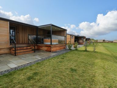 Exterior of wooden lodges with patios and a grassy lawn at Math Lodge 3 in Llanelidan near Corwen