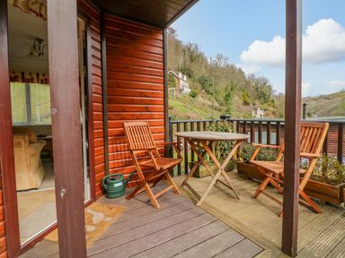 A wooden deck with a round table and two chairs outside a house with a view of hills at 22 Two Little Ducks in Lynton