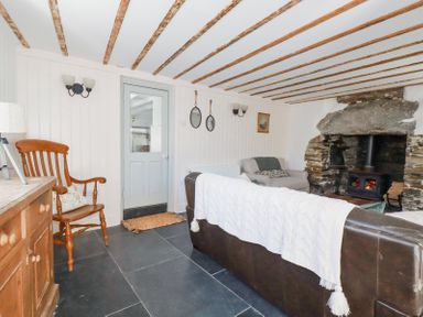 A living room with a leather sofa a wooden chair a stone fireplace and a wooden cabinet at Hilldene in Treknow