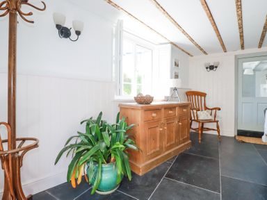 A room with a wooden cabinet plant a wooden chair and a coat rack at Hilldene in Treknow