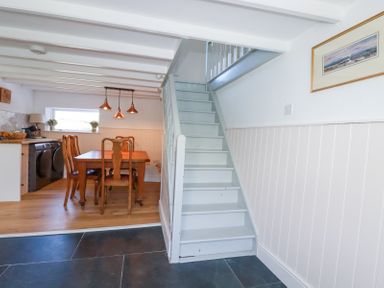 A kitchen and dining area with wooden table and chairs adjacent to a staircase at Hilldene in Treknow