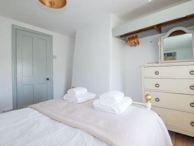 A bedroom with a bed with folded towels a chest of drawers with a mirror and a hanging rail with wooden hangers at Hilldene in Treknow