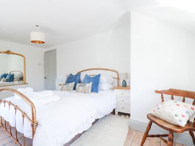 A bedroom with a brass bed frame bedside tables with lamps a wooden chair with a cushion and a large mirror at Hilldene in Treknow