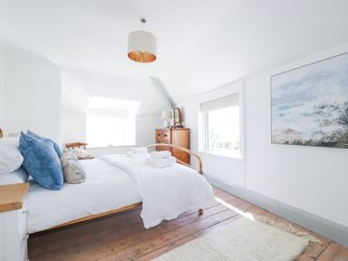 A bedroom with a bed blue pillows wooden floor a chest of drawers and a painting at Hilldene in Treknow