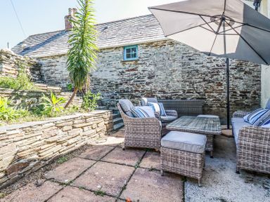 An outdoor patio area with wicker furniture including chairs and a table under a large umbrella at Hilldene in Treknow